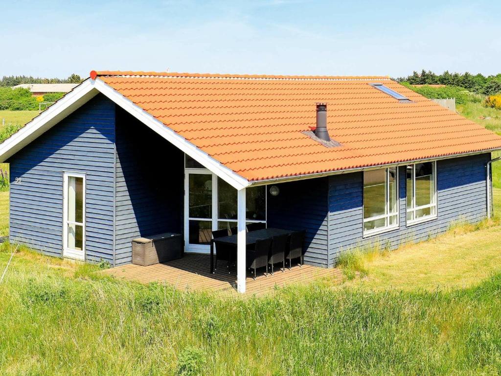a blue house with a deck in a field at 6 person holiday home in Ulfborg in Fjand Gårde