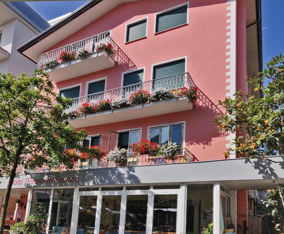 een roze gebouw met bloemen op de balkons bij Locanda Fabrizio in Caorle