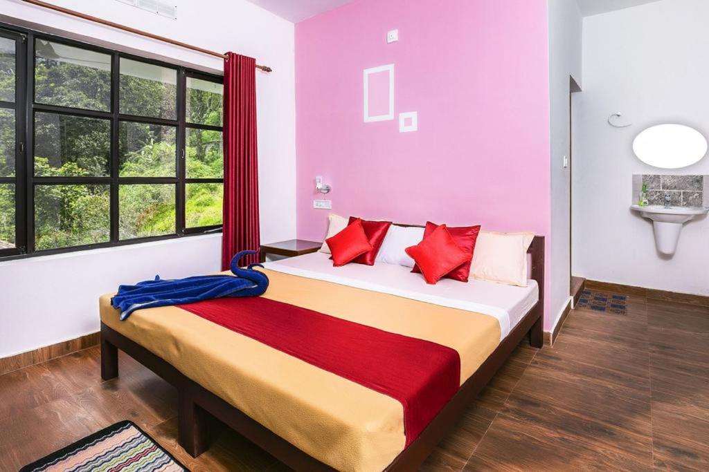 um quarto com uma cama grande e almofadas vermelhas em Grace Inn Munnar Homestay em Munnar