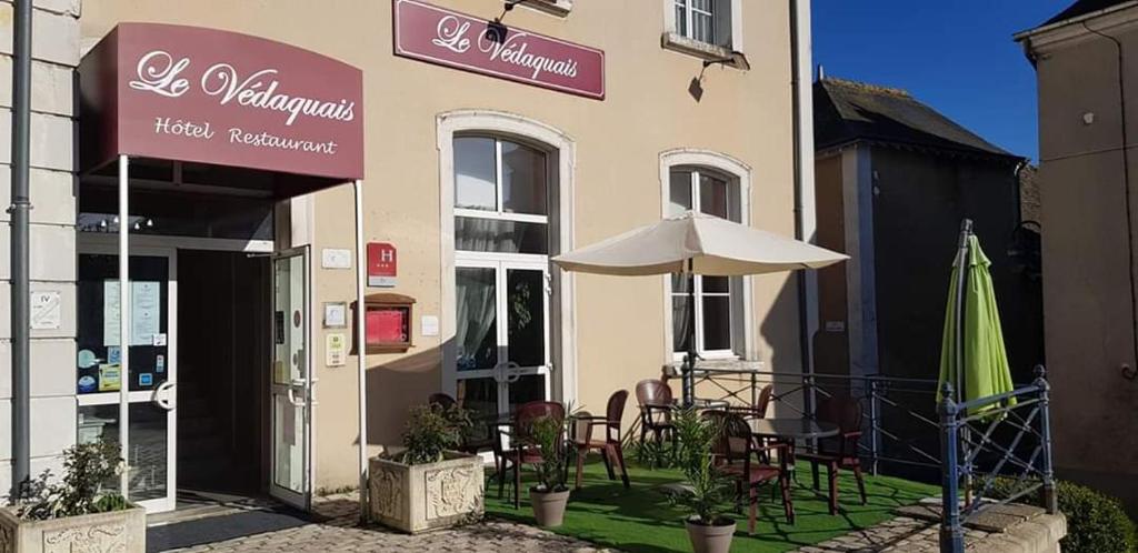 un restaurant avec des tables, des chaises et un parasol dans l'établissement Logis Hotel Restaurant Le Vedaquais, à Vaas