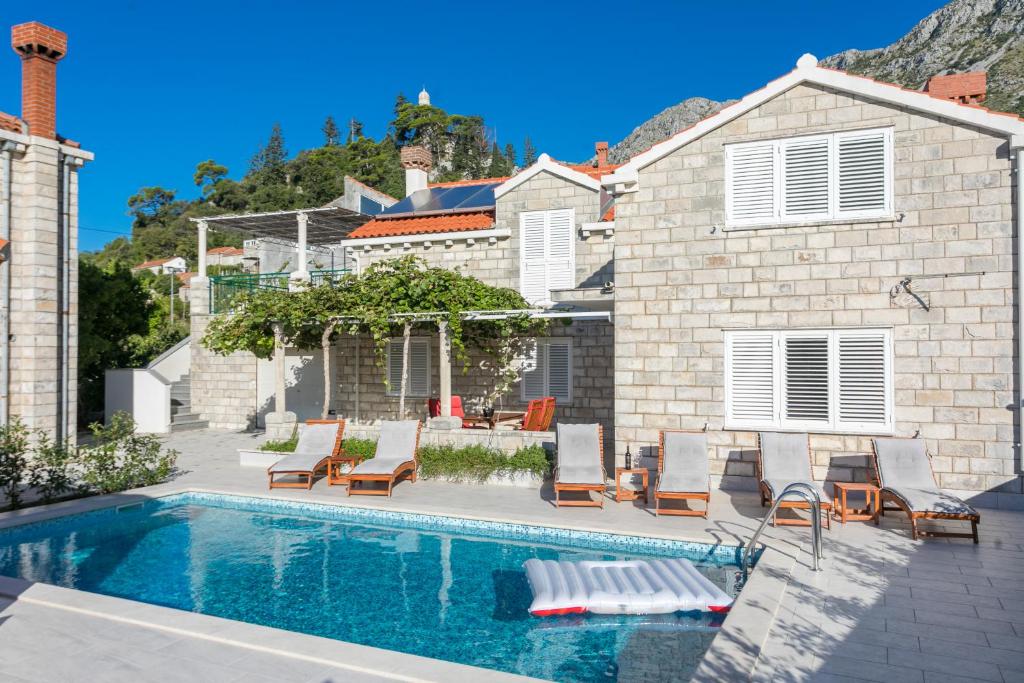 einen Pool mit Stühlen und ein Haus in der Unterkunft Villa Fortunei in Mokošica