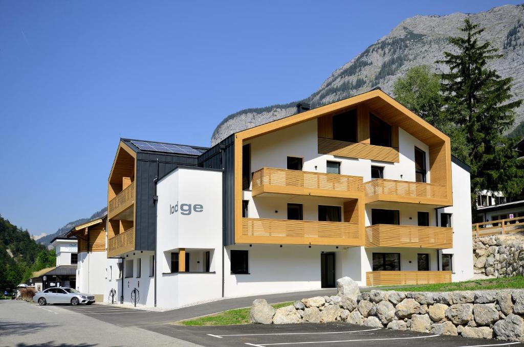 a white building with wooden balconies and a mountain at Brandlhof lodge in Saalfelden am Steinernen Meer
