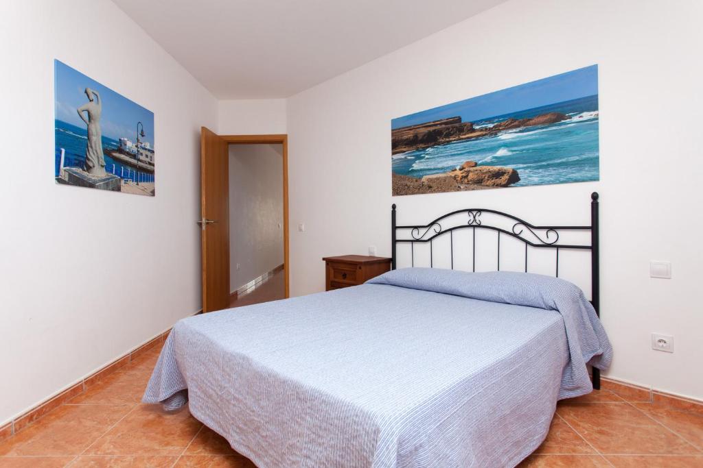 a bedroom with a bed and paintings on the wall at TAO El Cotillo in El Cotillo