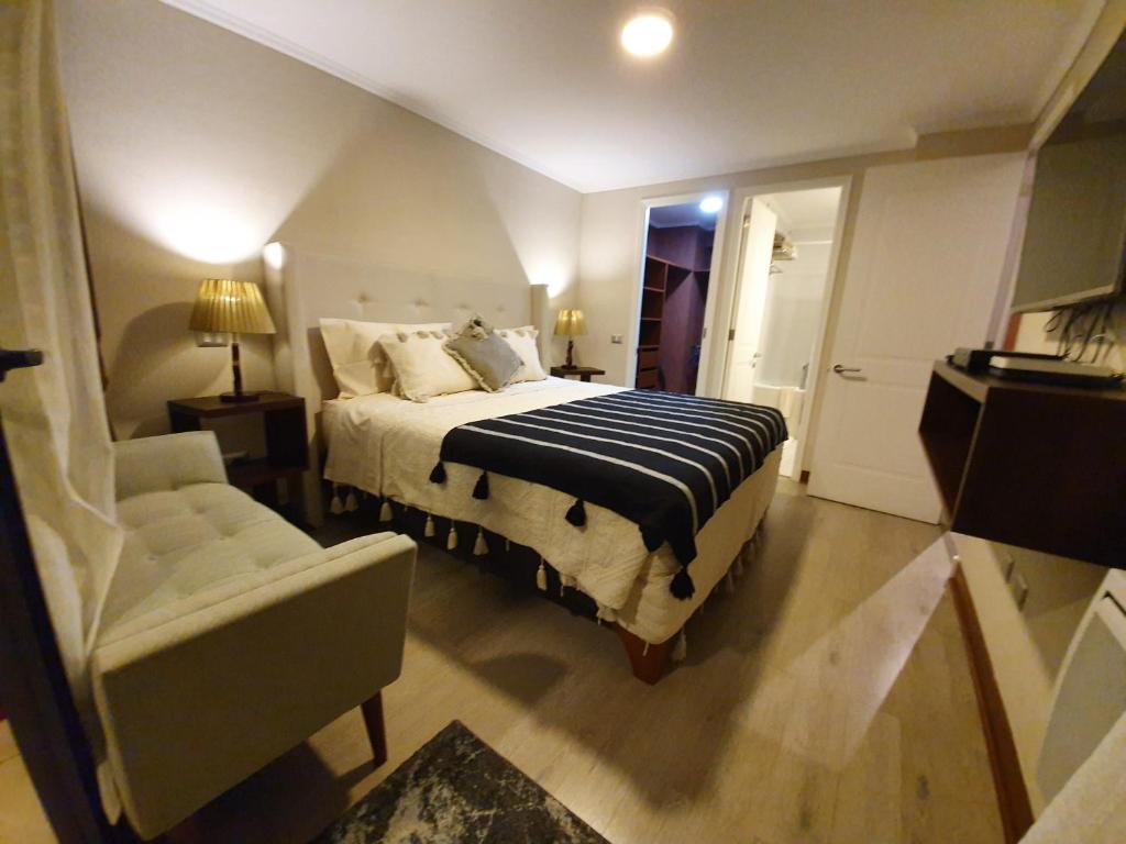 ein Schlafzimmer mit einem Bett, einem Sofa und einem Stuhl in der Unterkunft Mojens Suites Santiago in Santiago