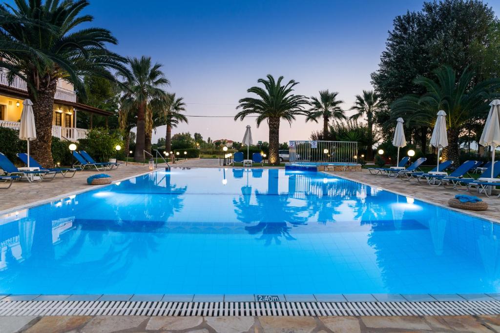 a large pool with blue water and palm trees at Kalidonio Studios in Kalamaki