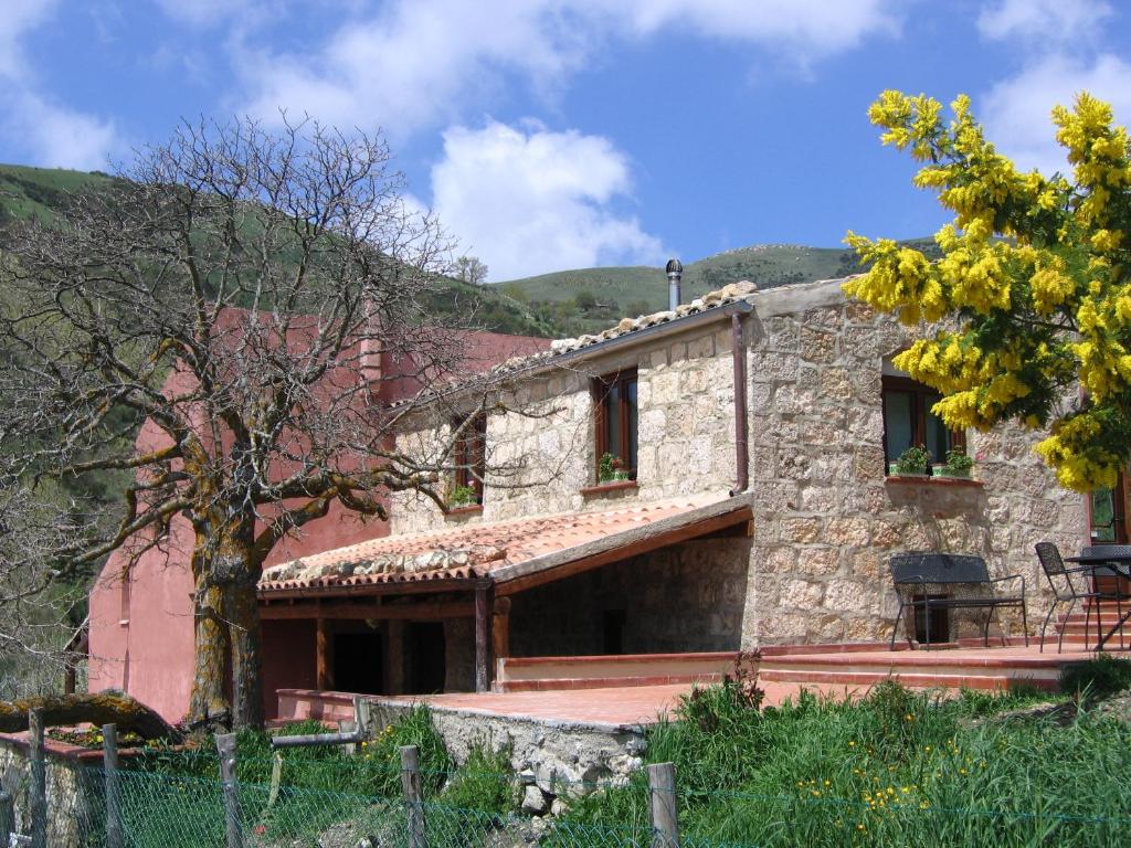a large stone house with a tree in front of it at Agriturismo Gelso in Castellana Sicula