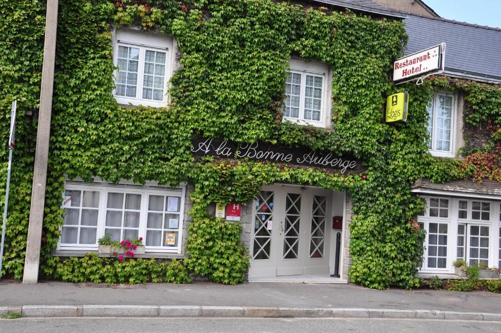 un bâtiment recouvert de lierre vert avec une porte dans l'établissement Logis Hôtel A la Bonne Auberge, à Laval