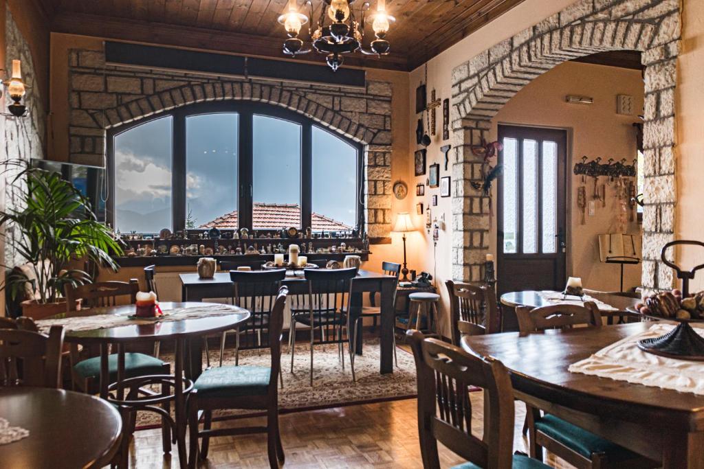 a restaurant with tables and chairs and a large window at Semeli Guesthouse in Karpenisi