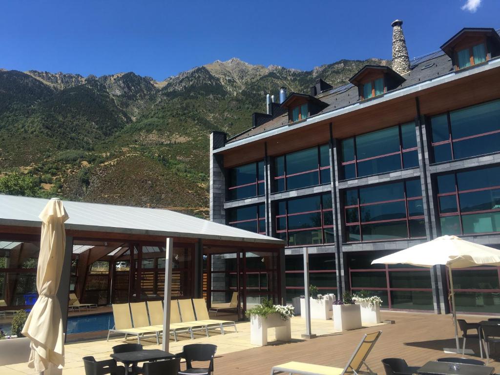 un hotel con mesas y sillas y montañas en el fondo en SOMMOS Hotel Aneto, en Benasque