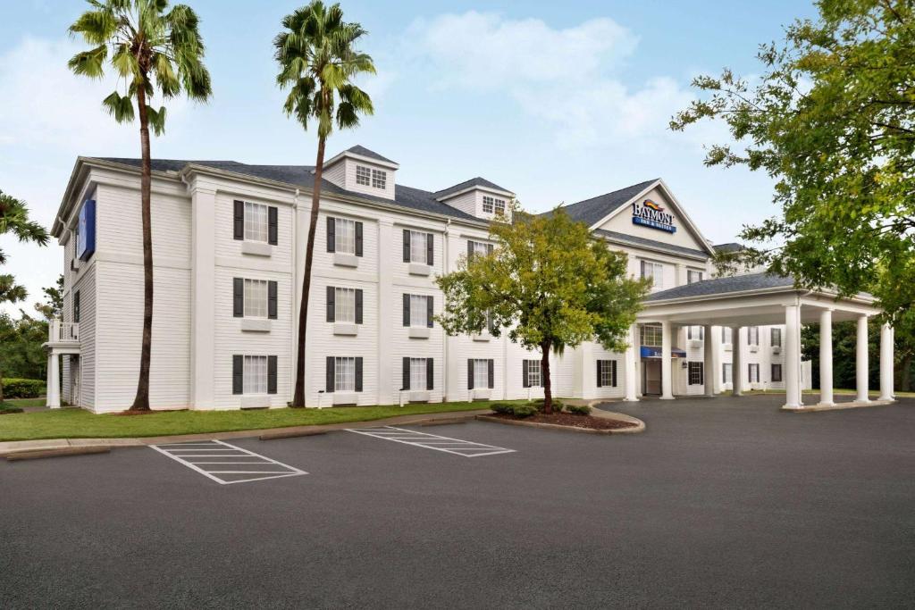 a white building with palm trees in a parking lot at Baymont by Wyndham Ormond Beach in Ormond Beach