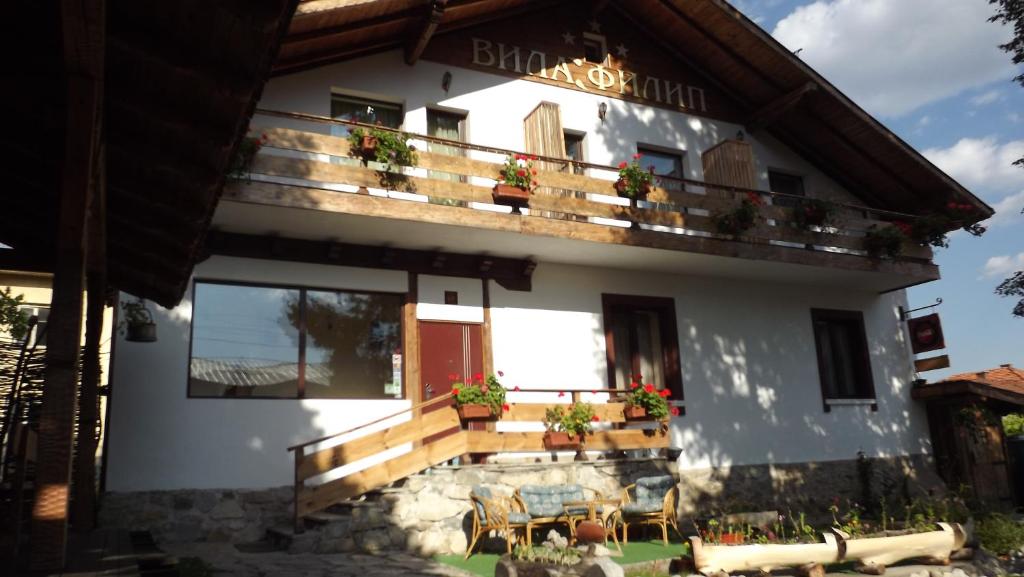 ein weißes Gebäude mit einem Balkon mit Topfpflanzen in der Unterkunft Villa Filip in Bachevo