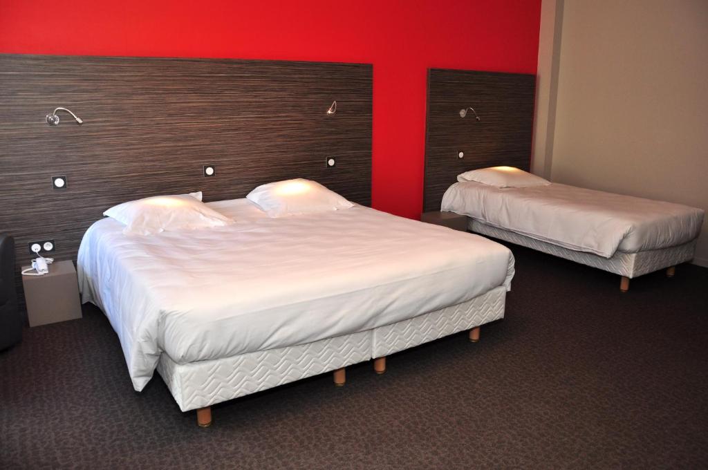 two beds in a hotel room with a red wall at Logis Hôtel A la Bonne Auberge in Laval