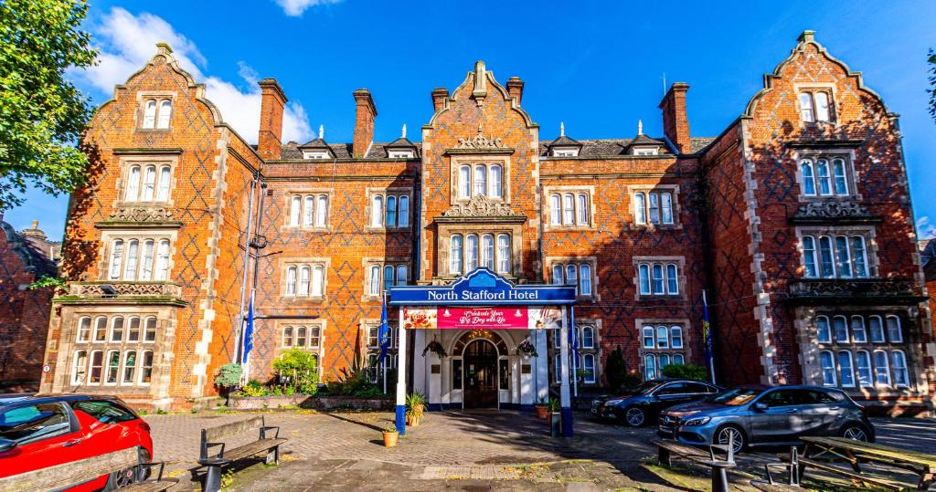 un viejo edificio con coches aparcados delante de él en North Stafford Hotel en Stoke on Trent