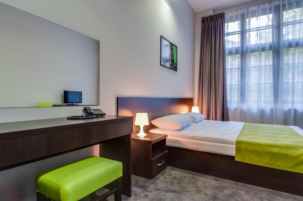 a hotel room with a bed and a desk and window at Apartamenty Grępielnia in Bielsko-Biała