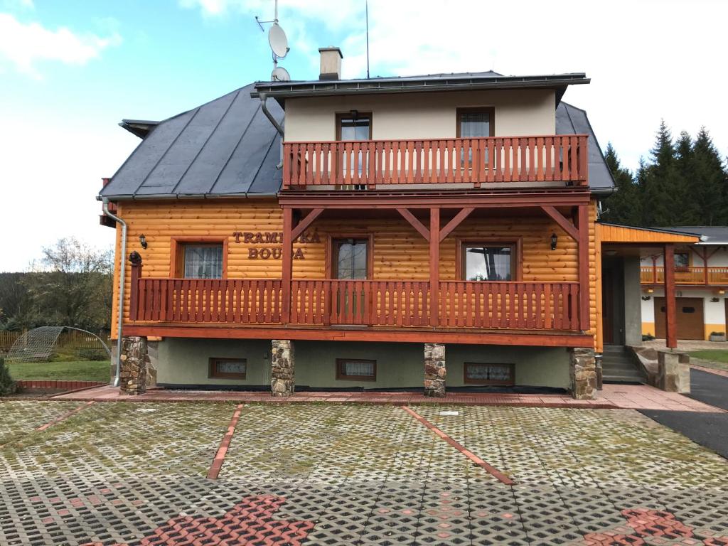 a large wooden house with a deck on a driveway at Penzion Trampska Bouda in Abertamy