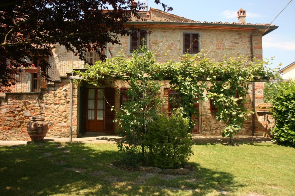 an old stone house with a tree in front of it at Pozzonovo in Castiglion Fiorentino