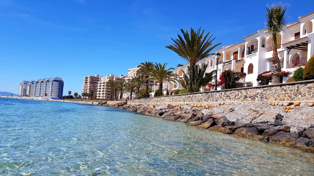 a beach with buildings and palm trees next to the water at Apartament Veneziola in San Javier