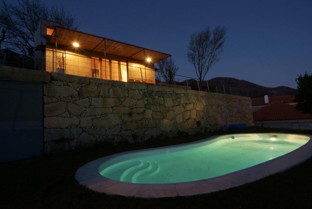 einem Pool vor einer Steinmauer und einem Haus in der Unterkunft Casa da Cerejeira - Casas de Alem - Ecoturismo in Arcos de Valdevez