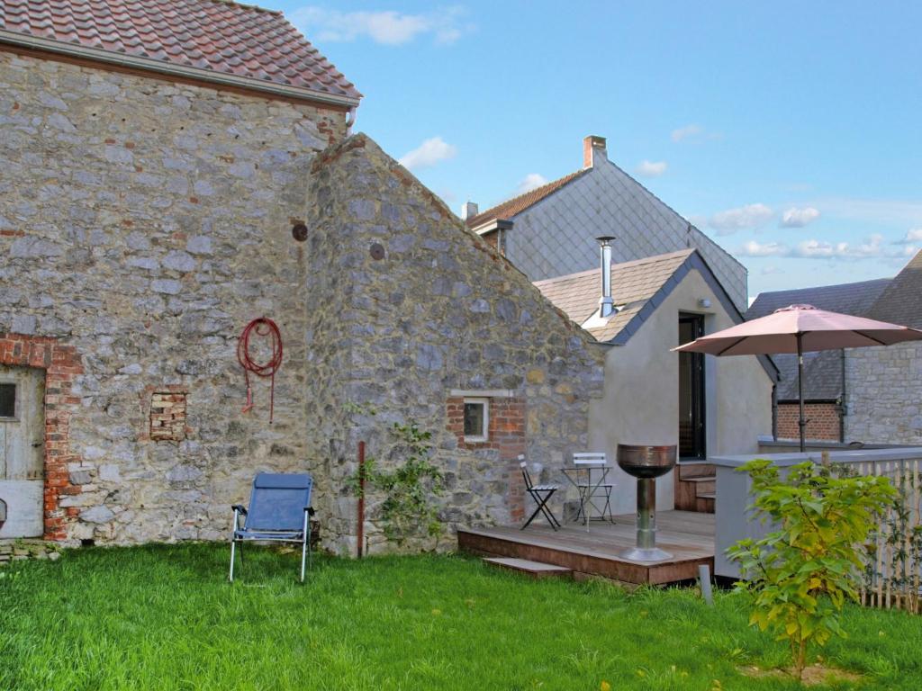 un edificio de piedra con terraza y sombrilla en Villa Le Ti' Bauduin by Interhome, en Thy-le-Bauduin