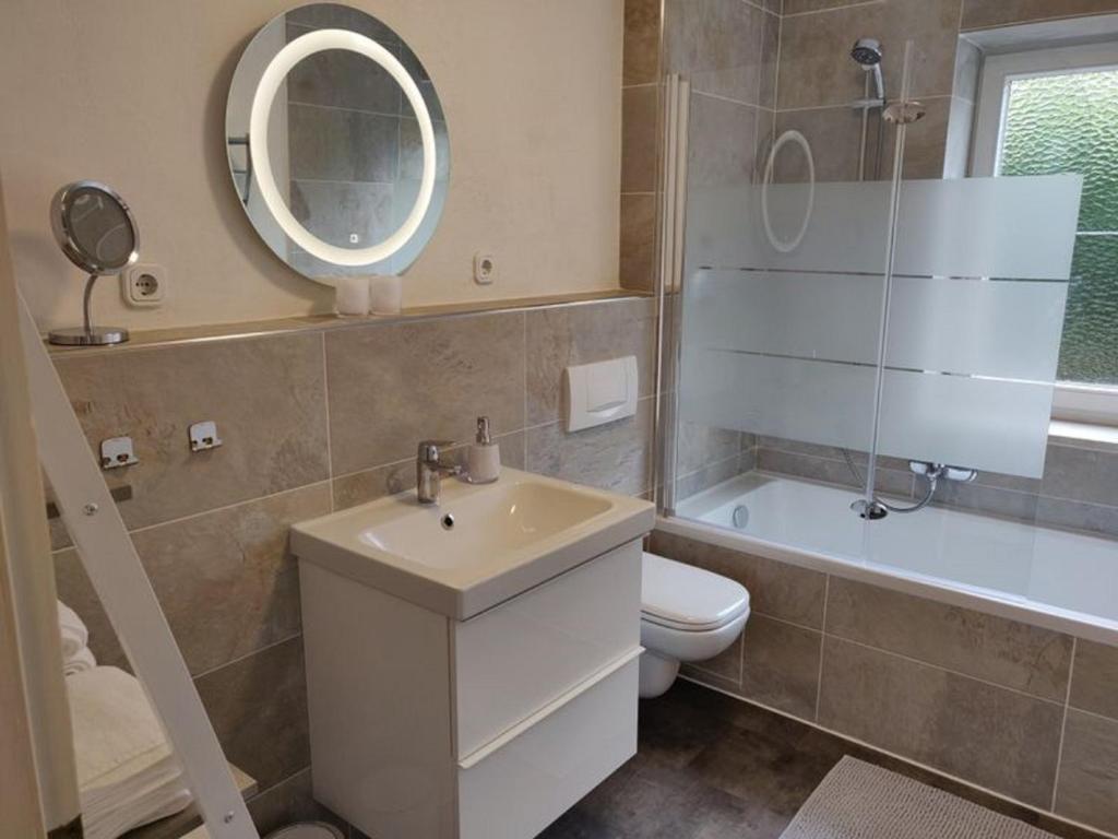 ein Badezimmer mit einem Waschbecken, einem WC und einem Spiegel in der Unterkunft Ferienwohnung Sonnenhang in Pfronten