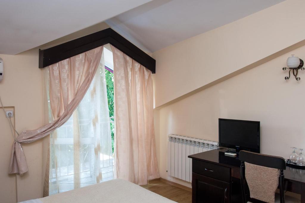 a bedroom with a bed and a window with a television at Pensiunea Splendid in Dorohoi