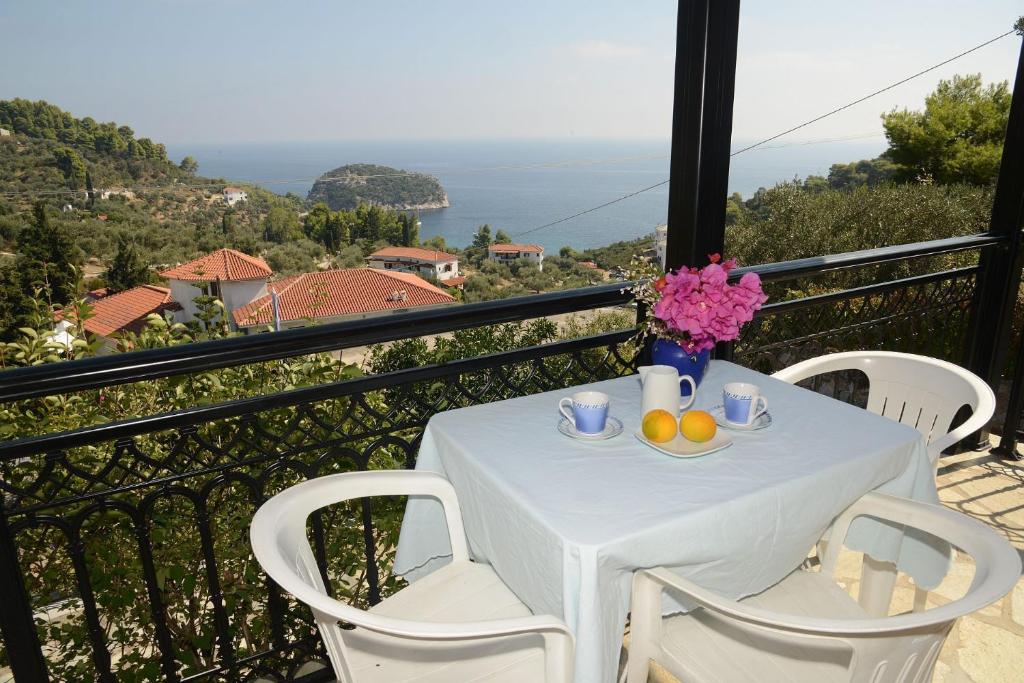 einen weißen Tisch mit Obst und Blumen auf dem Balkon in der Unterkunft Betsanis Stafylos Apartments in Stafylos