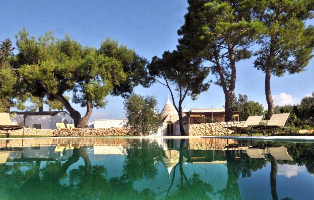 una piscina con alberi e una casa sullo sfondo di HelloApulia Trullo Amore Mio a Ceglie Messapica