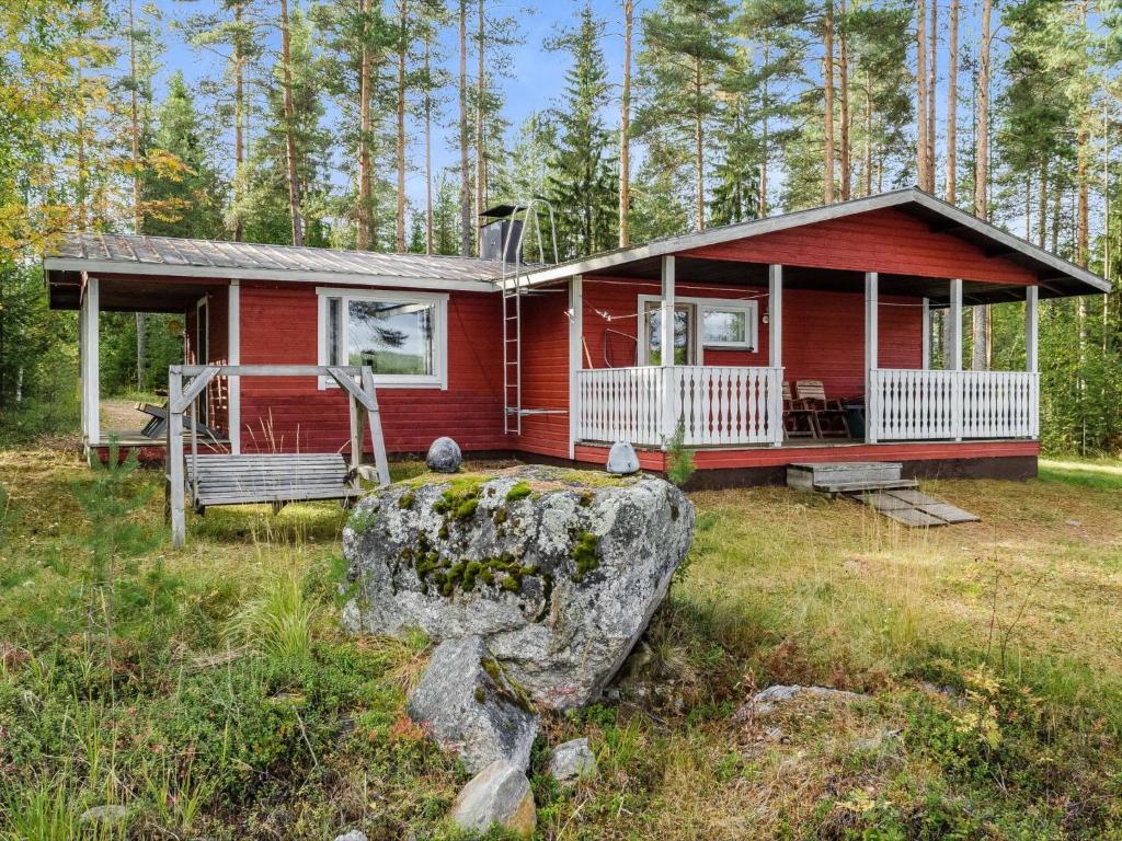 une maison rouge avec un grand rocher devant elle dans l'établissement Holiday Home Mäntylä by Interhome, à Nurmes