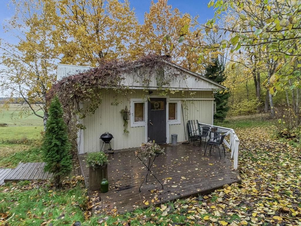 um pequeno barracão branco com uma mesa e cadeiras num deque em Holiday Home Päivärinne by Interhome em Tallnäs