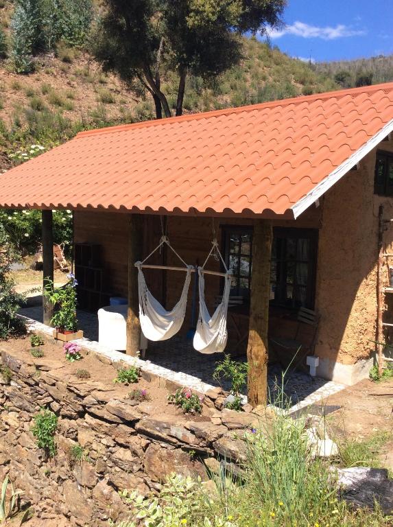 une maison avec un toit orange et des rideaux suspendus dans l'établissement Unique Tiny House with Natural Building Techniques, à Figueiró dos Vinhos