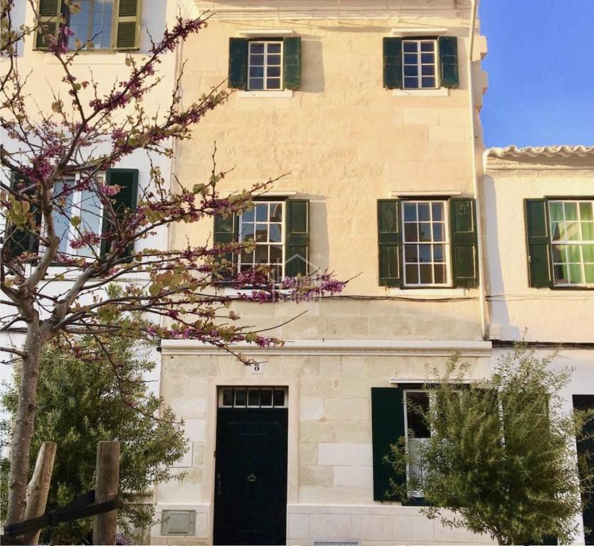 un edificio con una puerta negra y ventanas verdes en Sant Roc, en Mahón