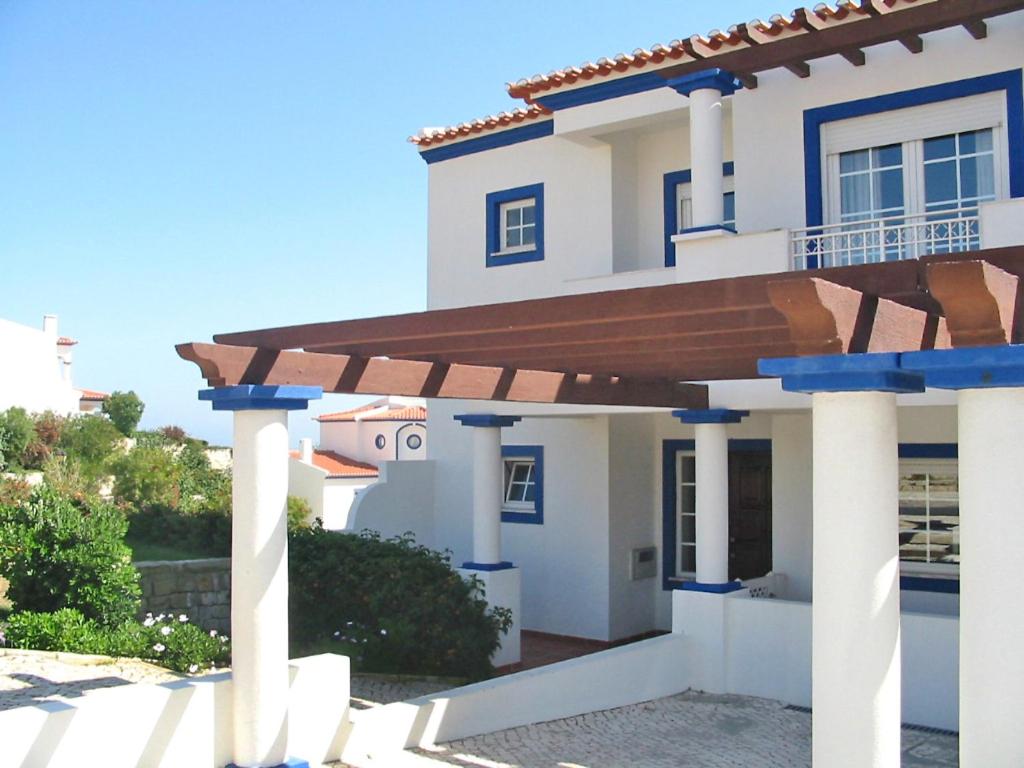 une maison blanche avec un toit en bois et des colonnes dans l'établissement Holiday Home Praia del Rey Golf Casa by Interhome, à Casal da Lagoa Seca