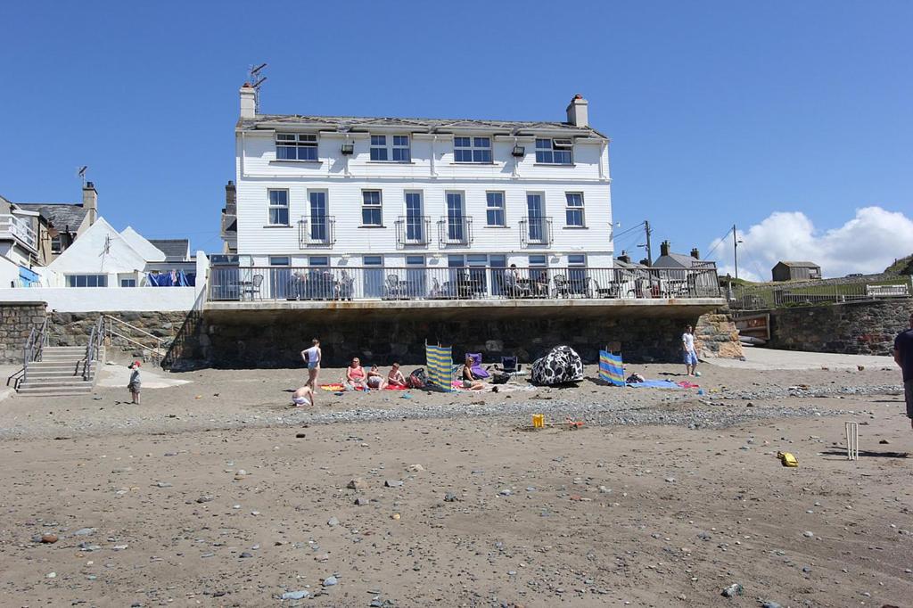 una gran casa blanca con gente en la playa en Gwesty Ty Newydd en Aberdaron