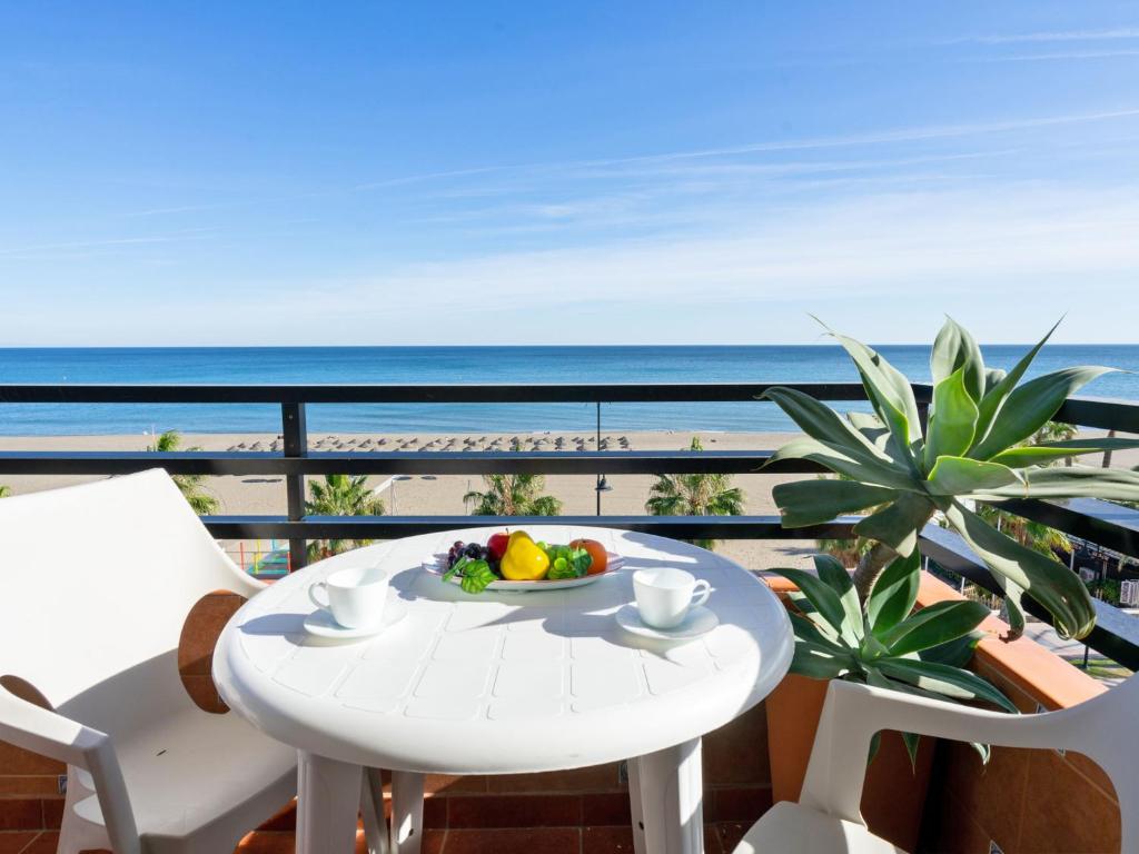 トレモリノスにあるApartment Apartamento Perla Del Solのビーチ沿いのバルコニーにテーブルとフルーツのボウルを用意しています。