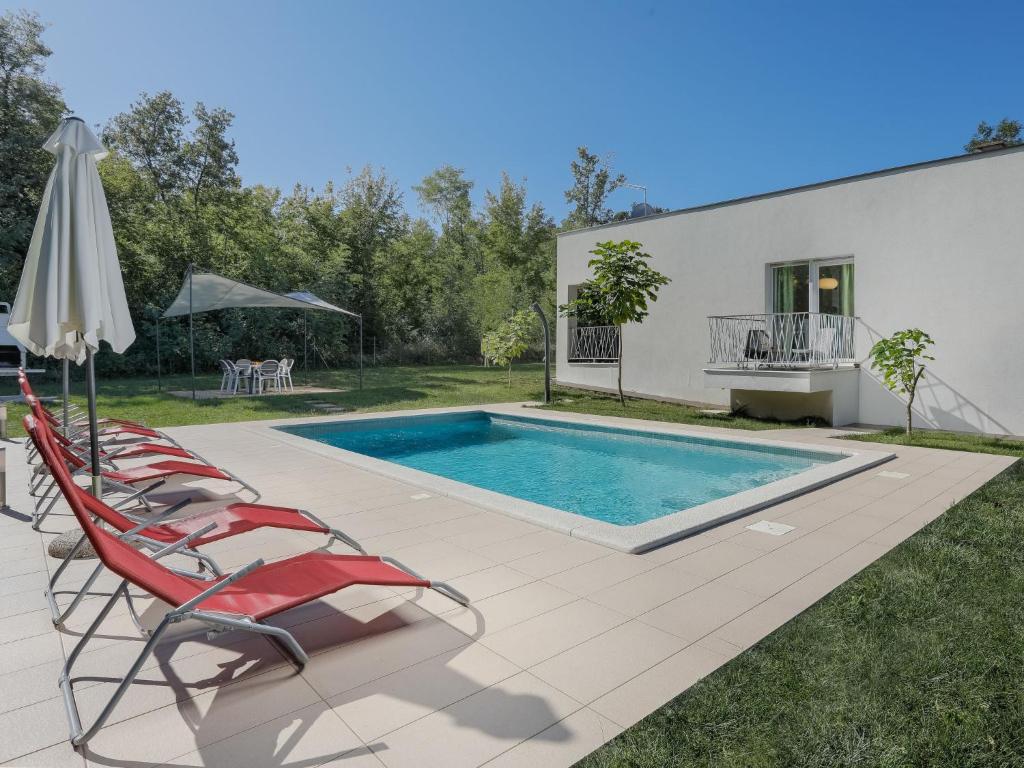 a swimming pool with chairs and an umbrella at Holiday Home Forest Fairy by Interhome in Raša