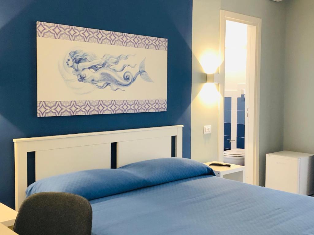 een blauwe slaapkamer met een bed en een schilderij aan de muur bij villa oltremare resort in Bagheria