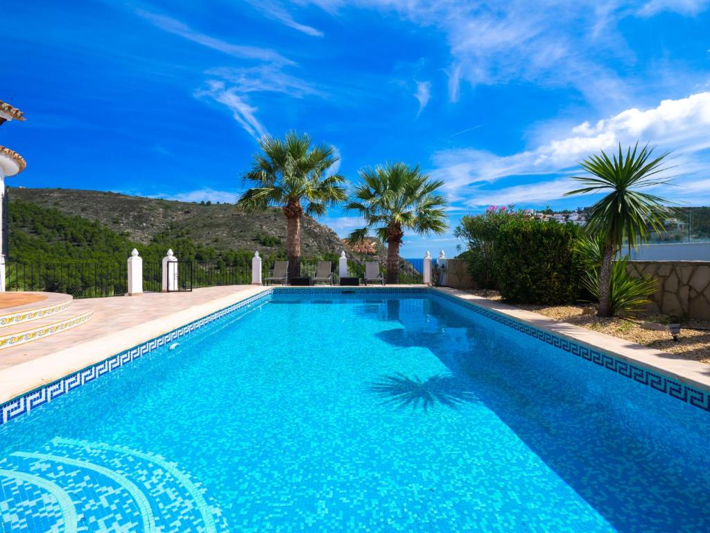 een zwembad met palmbomen en een blauwe lucht bij Villa Manana by Interhome in Moraira