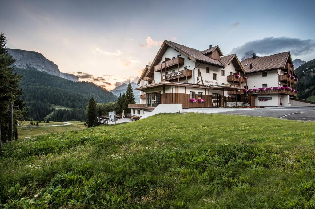 uma casa grande numa colina com um campo de relva em Hotel Arlara em Corvara in Badia