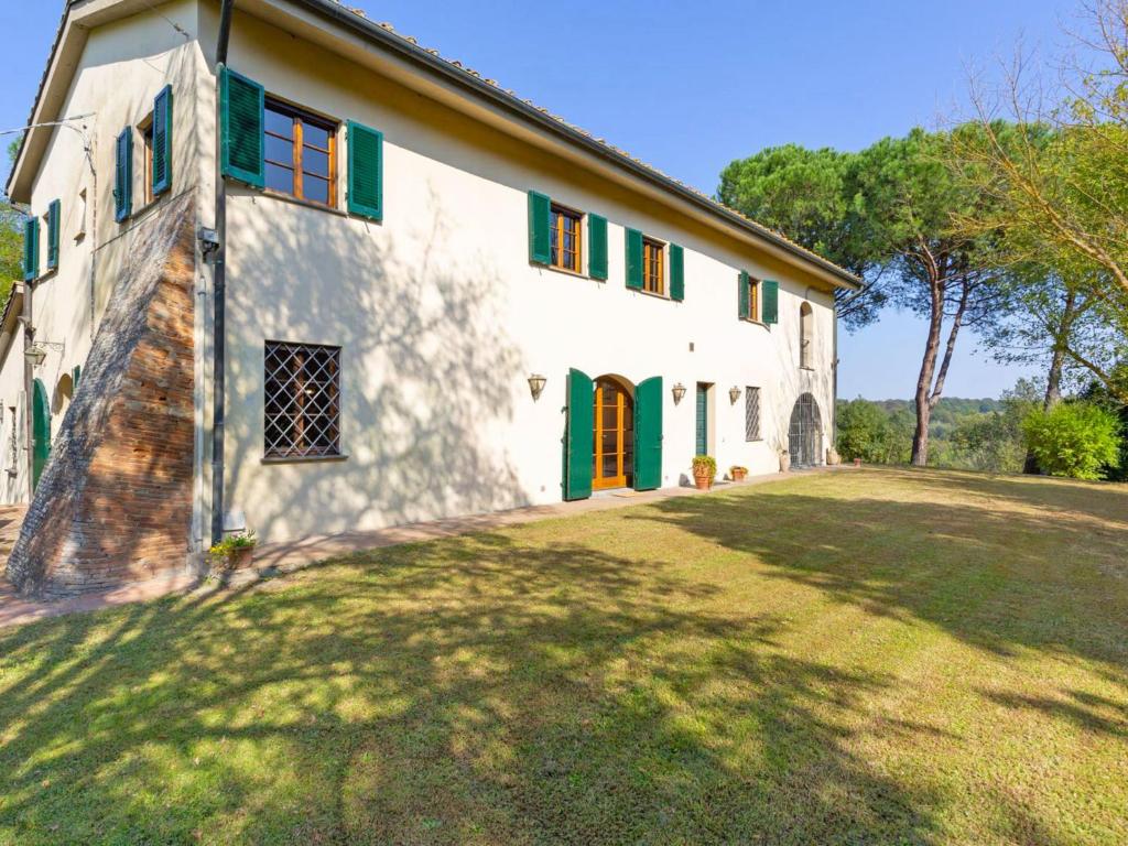 a large white house with green shutters and a yard at Holiday Home Villa San Gervasio by Interhome in Castiglione del Bosco