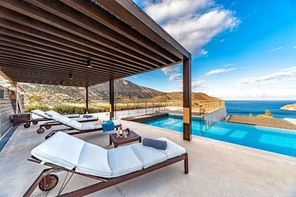 an outdoor patio with a pool and a view of the ocean at Elounda Lavender Villa in Elounda
