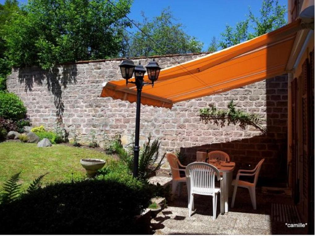 eine Terrasse mit einem orangenen Sonnenschirm, einem Tisch und Stühlen in der Unterkunft La Halte des Princes in Chantraine