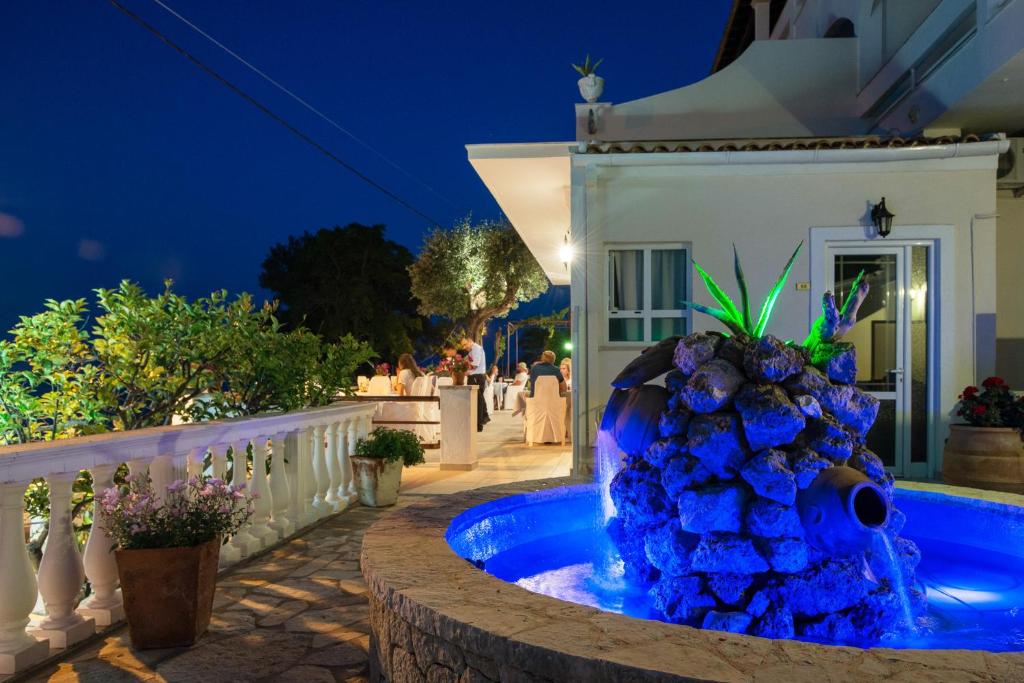 una fontana blu di fronte a una casa di notte di Hotel Kaiser Bridge a Benitses