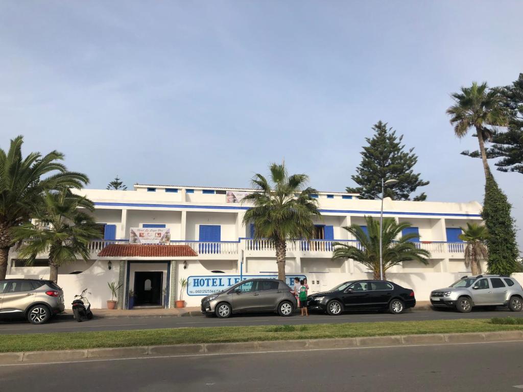 沃利迪耶的住宿－Le Lagon Bleu Oualidia，一座白色的建筑,前面有汽车停放