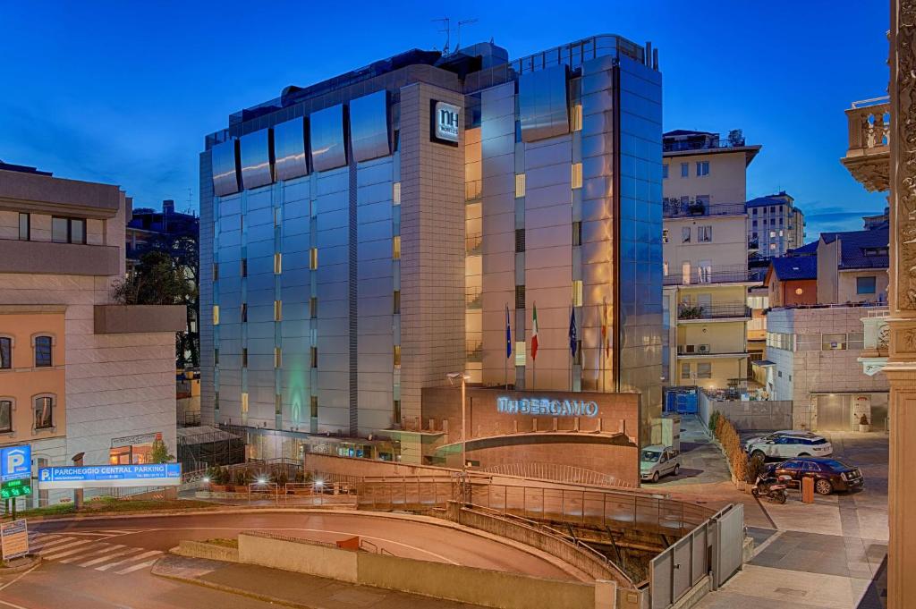 un grand bâtiment avec une horloge sur son côté dans l'établissement NH Bergamo, à Bergame