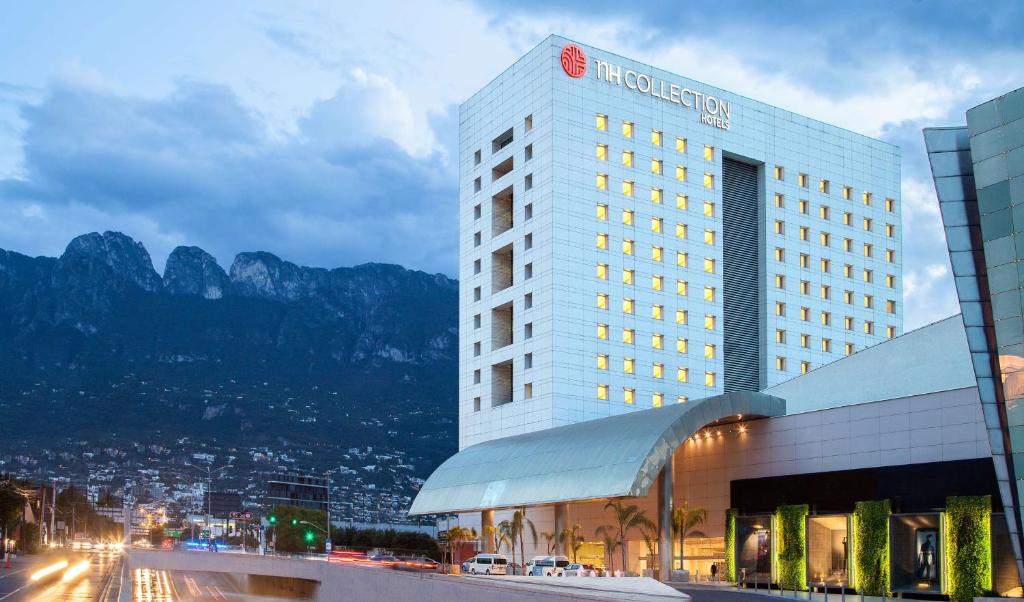 a hotel with a building with mountains in the background at NH Collection Monterrey San Pedro in Monterrey