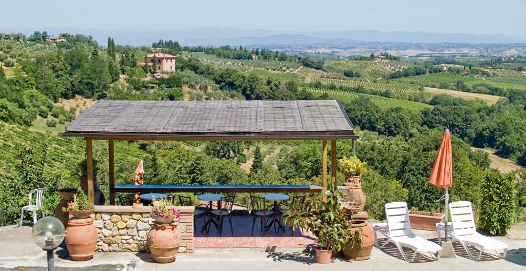 un cenador con sillas y sombrillas en una colina en B&B I Coppi, en San Gimignano