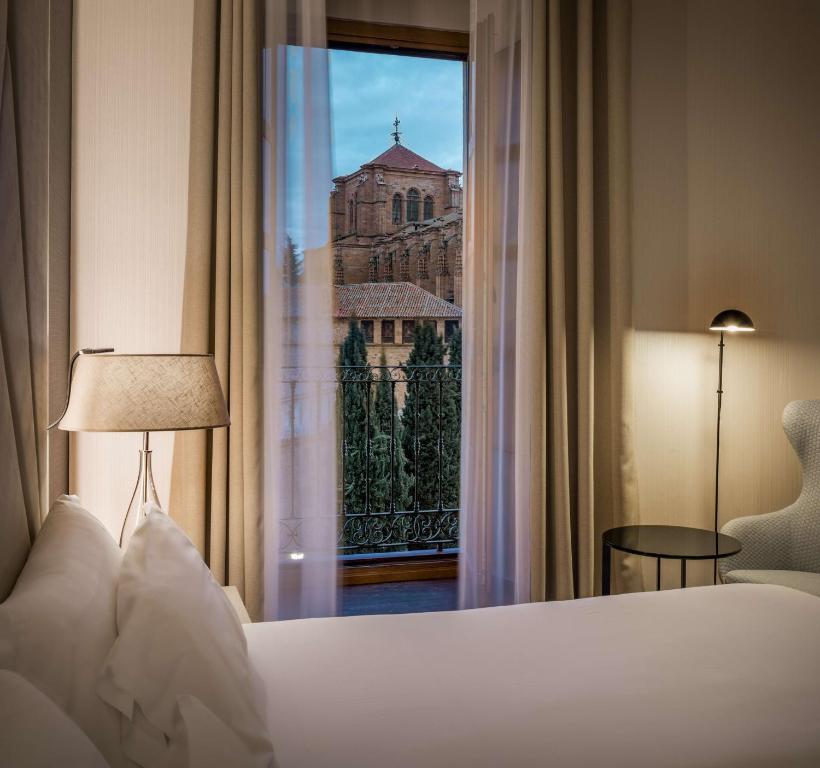 - une chambre avec un lit et une vue sur un bâtiment dans l'établissement NH Collection Salamanca Palacio de Castellanos, à Salamanque
