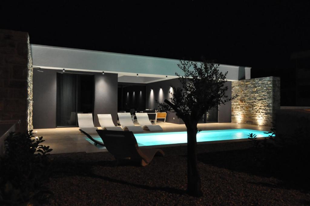 a living room with a couch and a pool at night at Homes4you K3 in Pašman