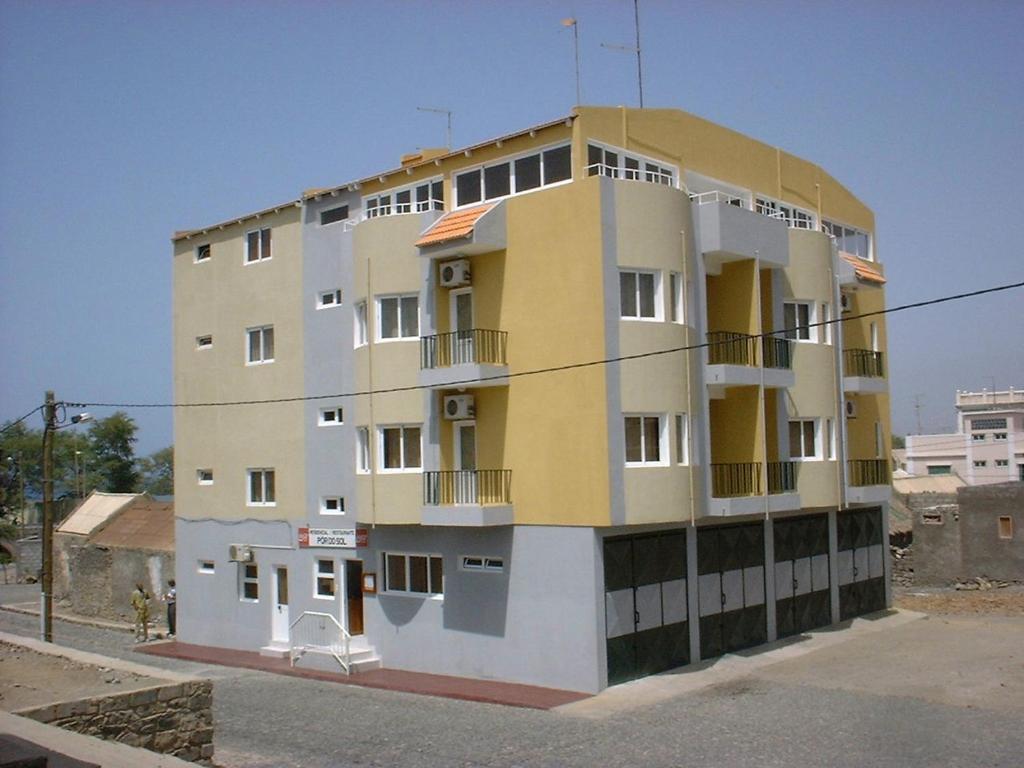 un edificio amarillo y blanco al lado de una calle en Residencial Pôr do Sol, en Porto Novo