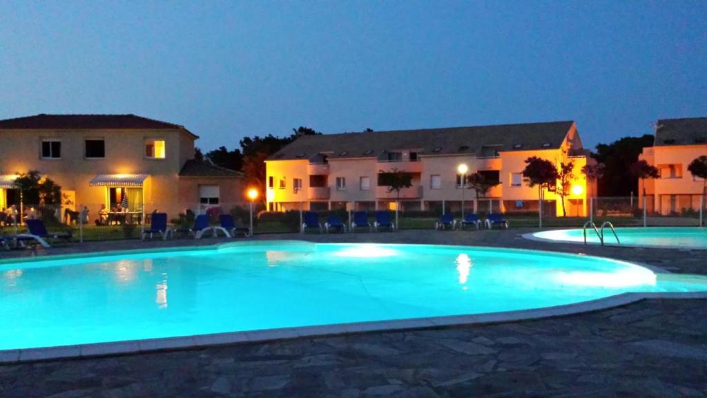 a large blue swimming pool in front of some buildings at Domaine de Mélody in Moriani Plage